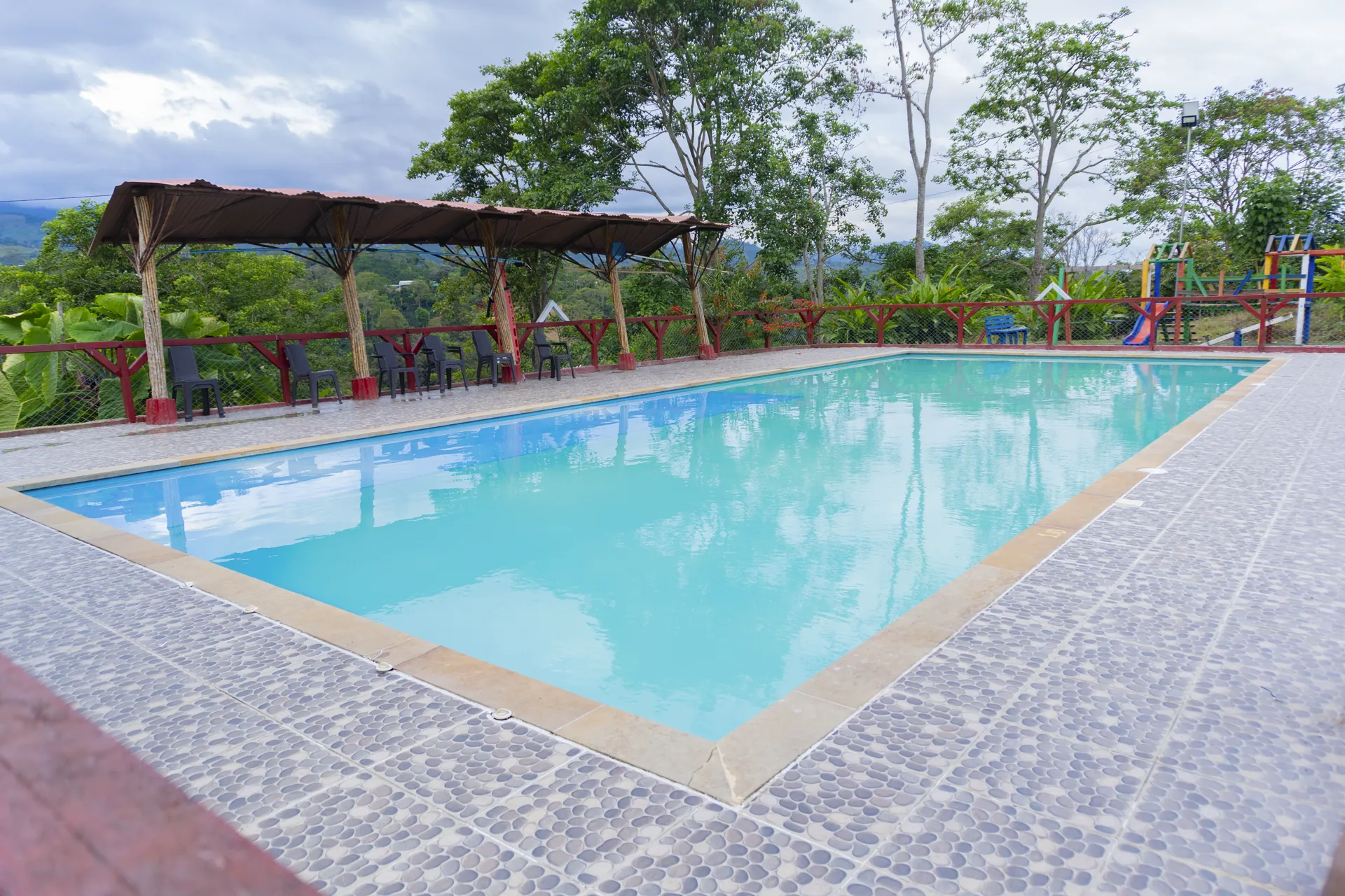 Piscina de la finca rodeada de zonas de descanso y juegos, con vista al paisaje del Huila