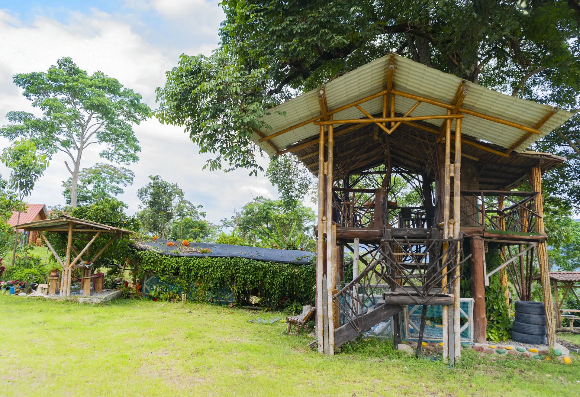 Zona de juegos infantil con estructura de madera y techo metálico en la finca
