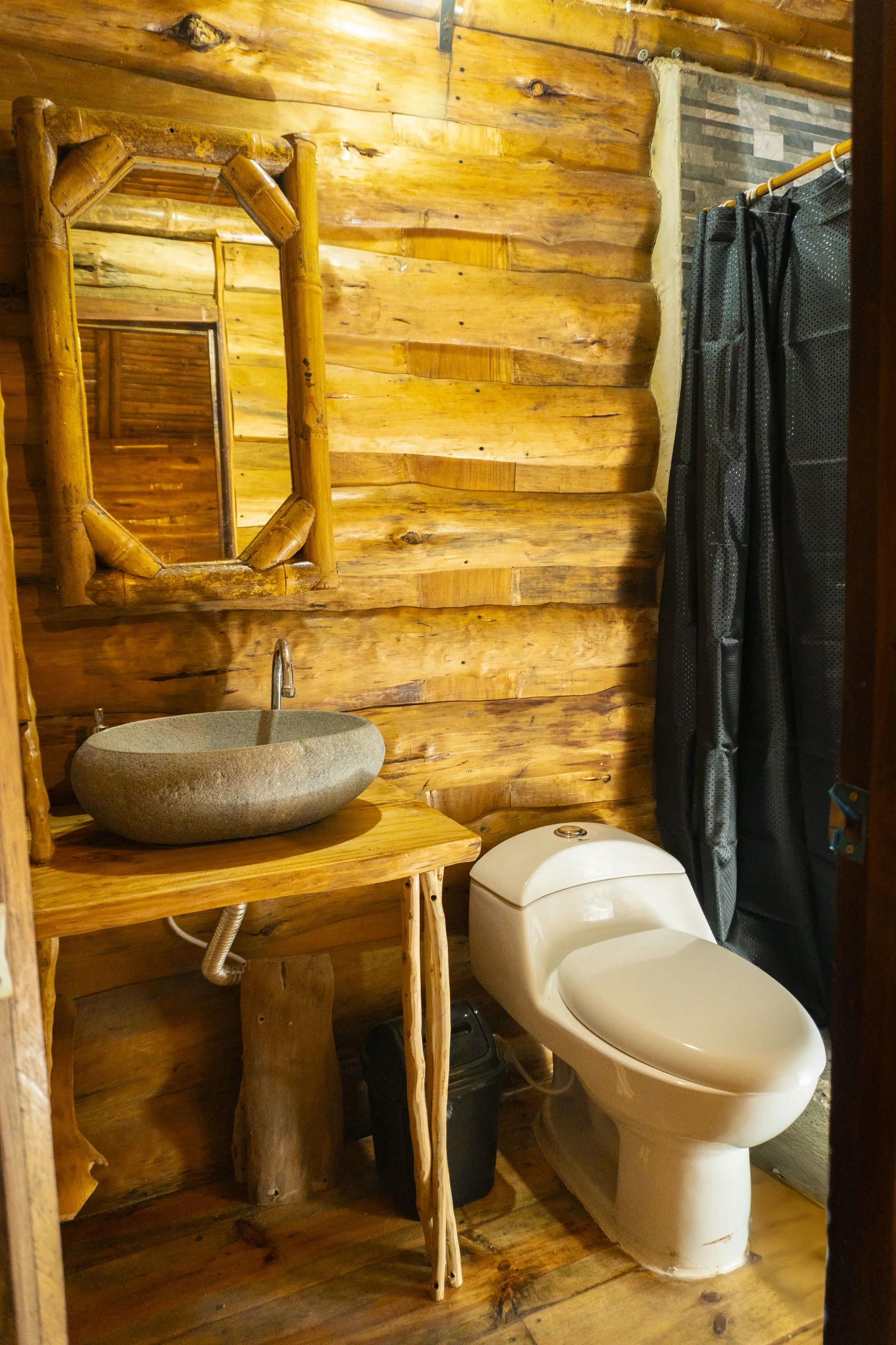 Baño de cabaña de madera con espejo, lavamanos y sanitario
