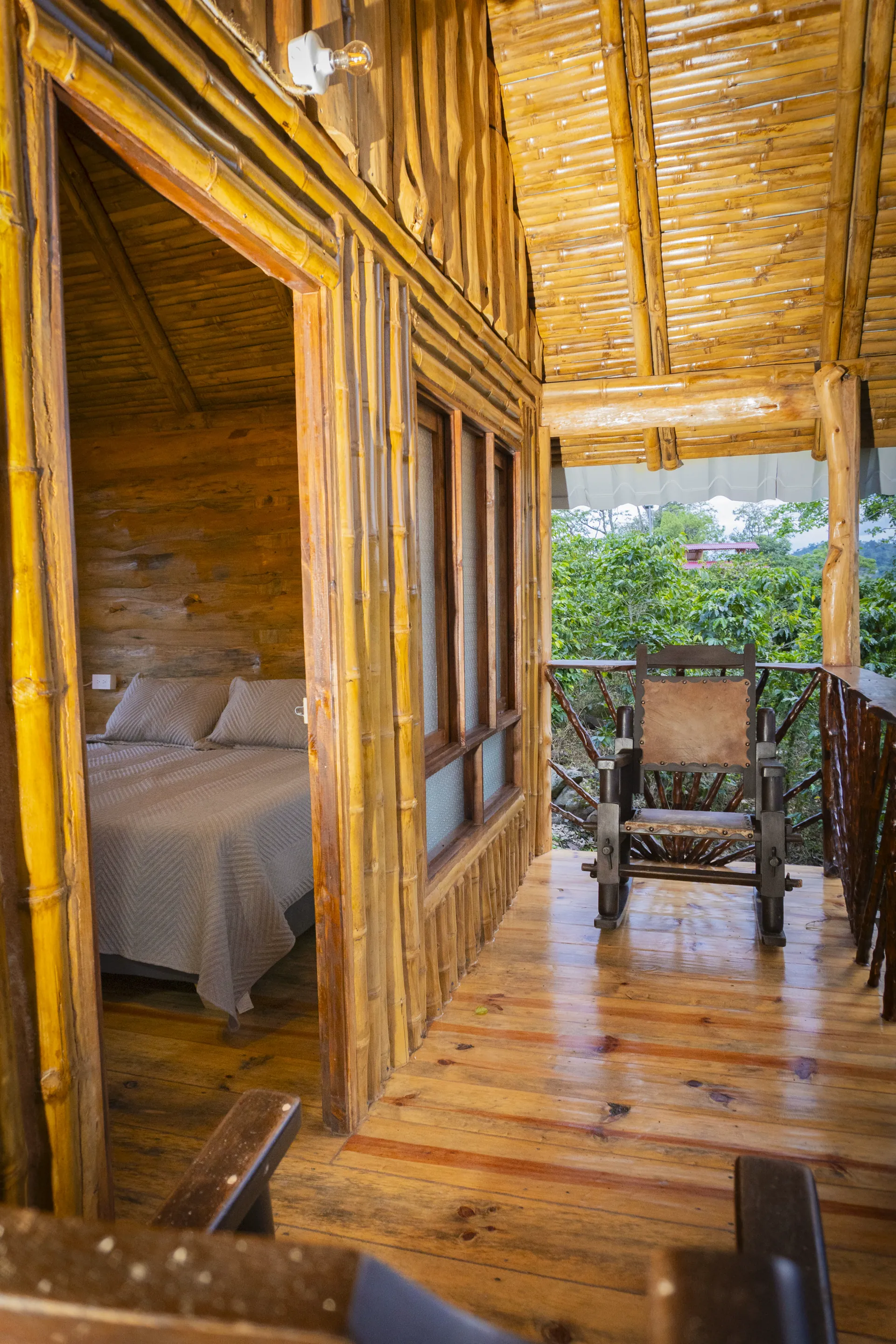 Interior de cabaña de madera con cama y salida hacia un balcón