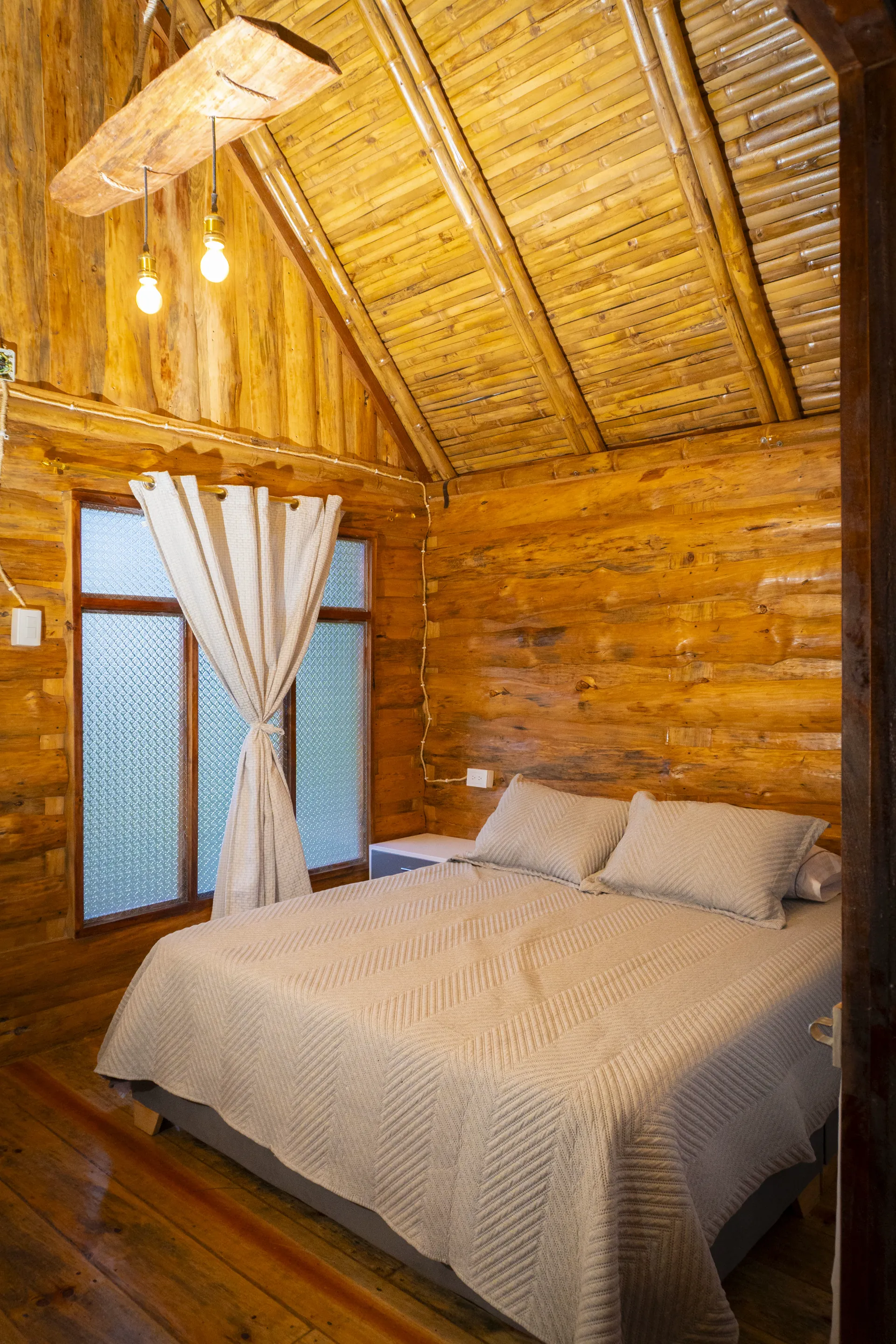 Habitación de cabaña de madera con cama tendida y ventana